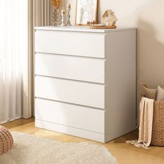 a white dresser sitting next to a window in a living room with a rug on the floor