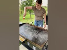 a woman standing over a grill with food on top of it in front of her