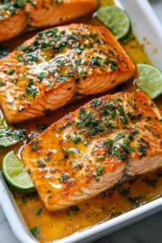 two salmon fillets in a baking dish with limes