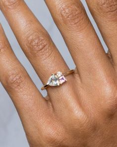 a woman's hand with an engagement ring on top of her left hand and the middle finger