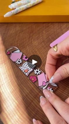 a woman is cutting out some stickers on a wooden table next to her nails