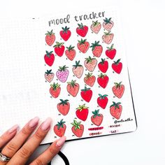 a person's hand holding a notebook with strawberries and strawberrys on it