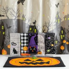 halloween decorations are on display in front of a curtain with black cats and pumpkins