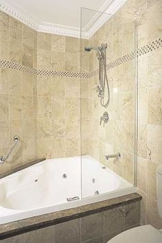 a bath tub sitting next to a toilet in a bathroom under a shower head mounted on a wall