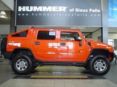 an orange hummer truck parked in front of a sign