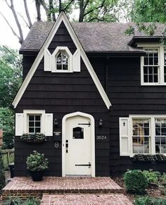 a black house with white shutters and an anteropoloide on the front door