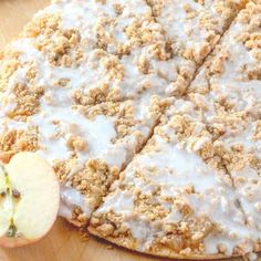 an apple pie with white icing and crumbs next to sliced apples on a cutting board