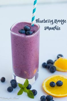 a smoothie with blueberries and orange slices on the side is ready to be eaten