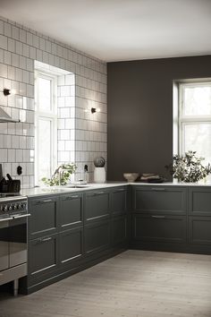 a large kitchen with gray cabinets and white tile on the walls is pictured in this image