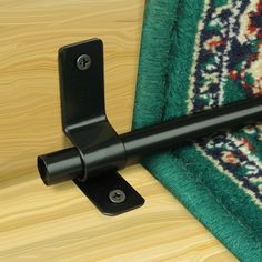 a close up of a black door handle on a green rug with a wooden floor