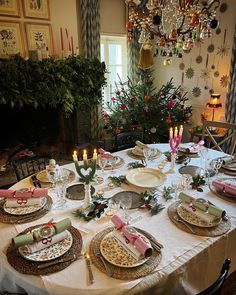 a table set for christmas dinner with plates and place settings