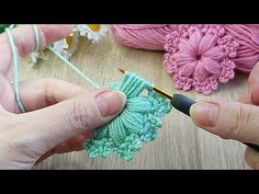 two hands crocheting together with yarn on a table