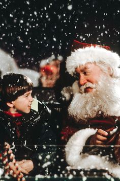 a little boy sitting next to santa clause