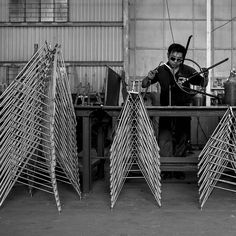 a man is working on some kind of thing in a factory with lots of sticks