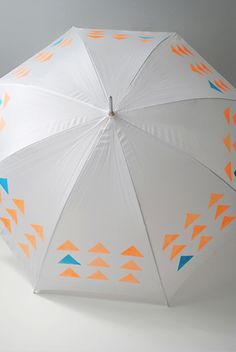 an umbrella with orange, blue and white designs on the inside is upside down against a gray background