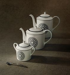 three teapots and a spoon on a table