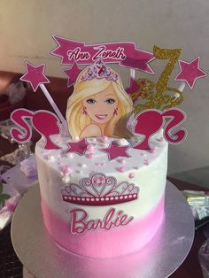 a pink and white cake with a barbie doll topper on it's side