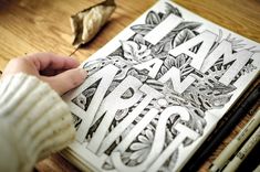 someone is drawing letters on a book with pencils