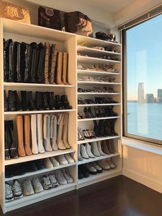 a closet filled with lots of shoes next to a large window overlooking the city skyline