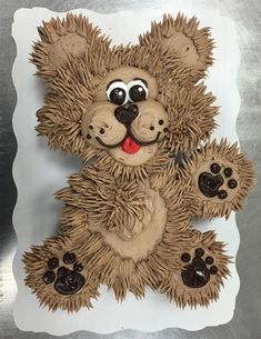 a teddy bear made out of paper on top of a white plate with paw prints