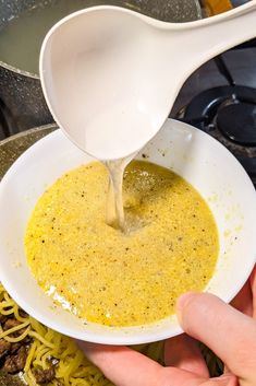 someone is pouring gravy into a bowl of noodles