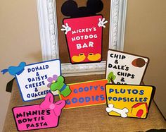 mickey mouse's hot dog bar and other signs on display in front of a door