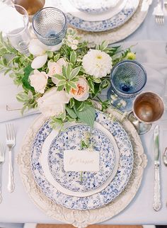 a table set with plates, silverware and flowers