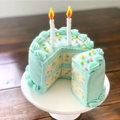 a birthday cake with two lit candles on top