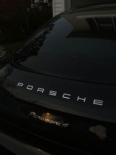 a black porsche parked in front of a house