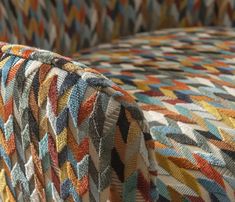 an upholstered couch with multicolored fabric on it's back and sides