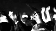 black and white photo of people raising their hands in the air at a music concert