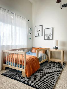 a small child's bed in a white room with two pictures on the wall