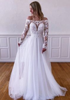 a woman wearing a white wedding dress with long sleeves and sheer lace on the top