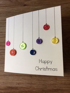 a christmas card with buttons hanging from strings