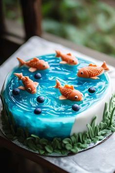 a cake decorated with goldfish and blueberries on top of a white table cloth