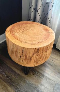 a round wooden table sitting on top of a hard wood floor next to a window