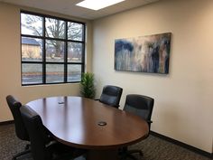 an empty conference room with a large wooden table and black chairs in front of a window