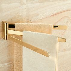 a towel rack with two towels hanging from it's sides and gold handles on the wall