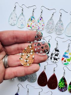 a hand holding a bunch of different colored earrings