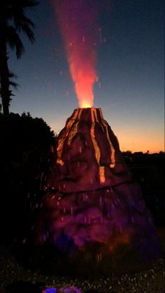 the volcano is lit up at night with red and yellow light coming from it's top