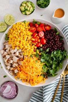 a bowl filled with corn, black beans, tomatoes and avocado on top of a white table