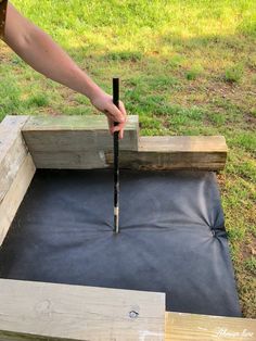 a person is holding a tool in the middle of a piece of wood that has been placed on top of it