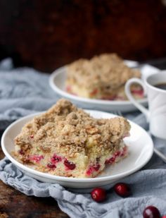 cranberry coffee cake on a white plate with a cup of coffee in the background