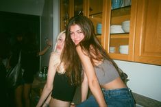 two young women standing next to each other in a kitchen