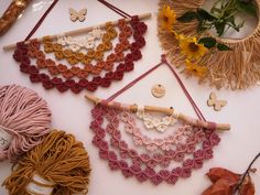 several crocheted items are arranged on a table with flowers and yarns in the background