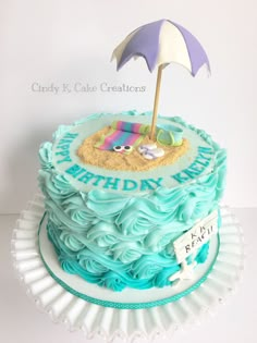 a birthday cake decorated with an umbrella and beach scene on top is sitting on a plate