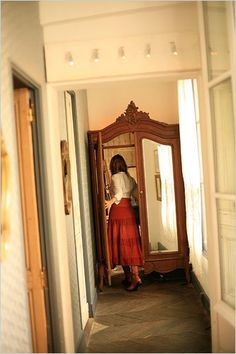 a woman standing in front of a mirror wearing a red skirt and white shirt with her hands on her hips