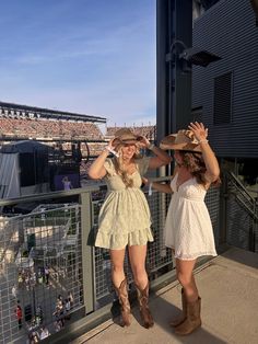 two women standing next to each other in front of a stadium