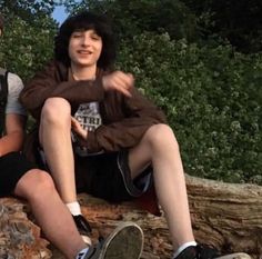 two young men sitting next to each other on rocks