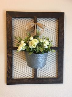 a metal bucket with flowers in it hanging on a wall